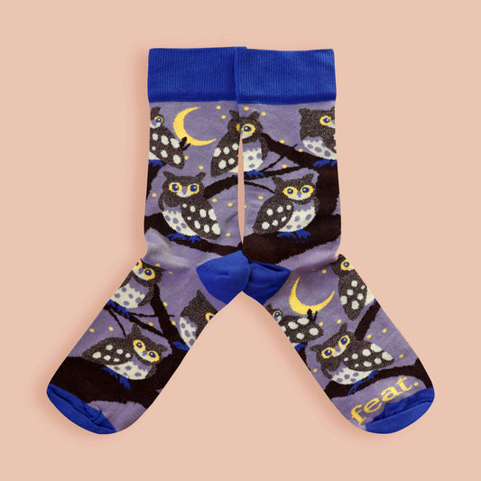 Owl-patterned socks with blue accents on a beige background