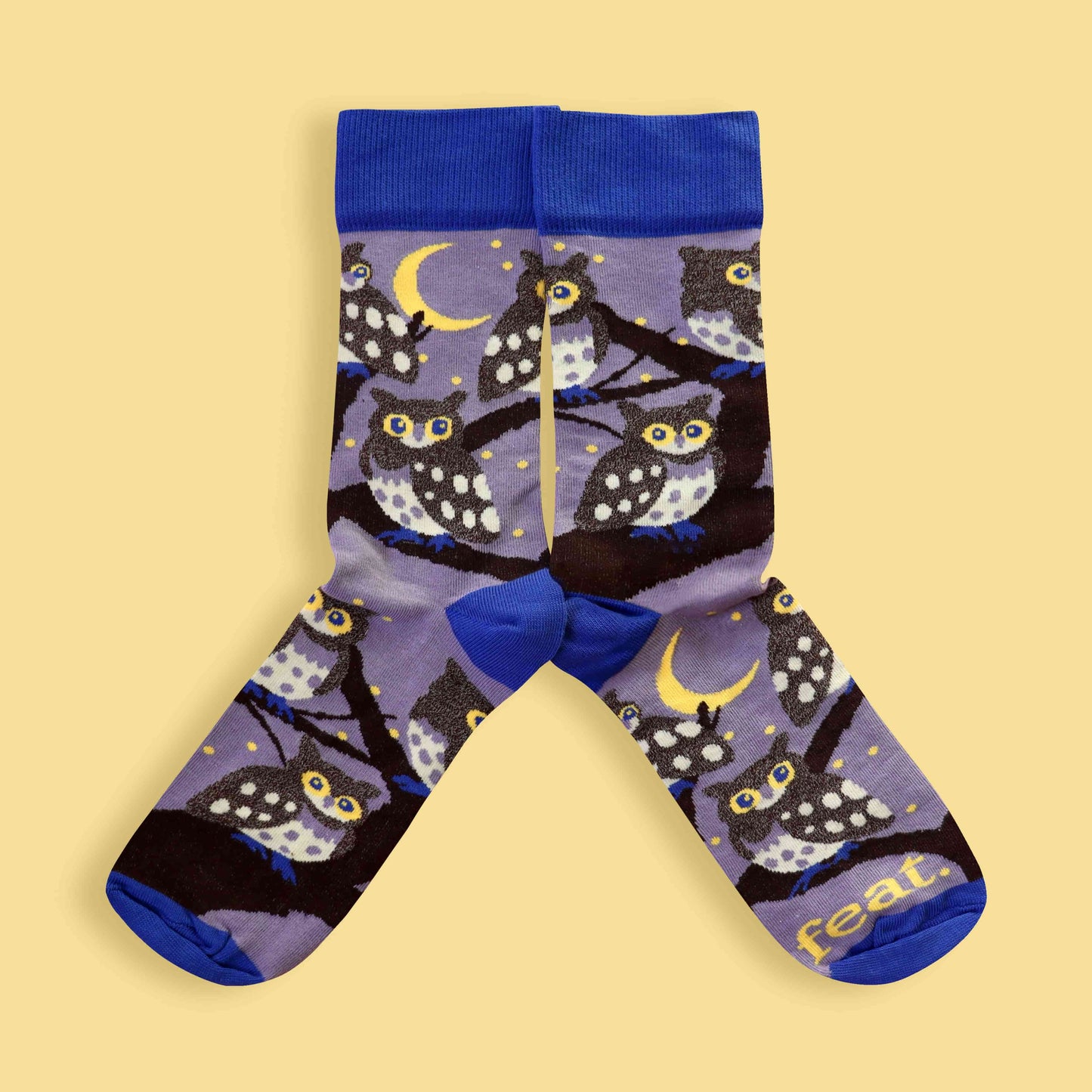 Owl-patterned socks with blue accents on a beige background